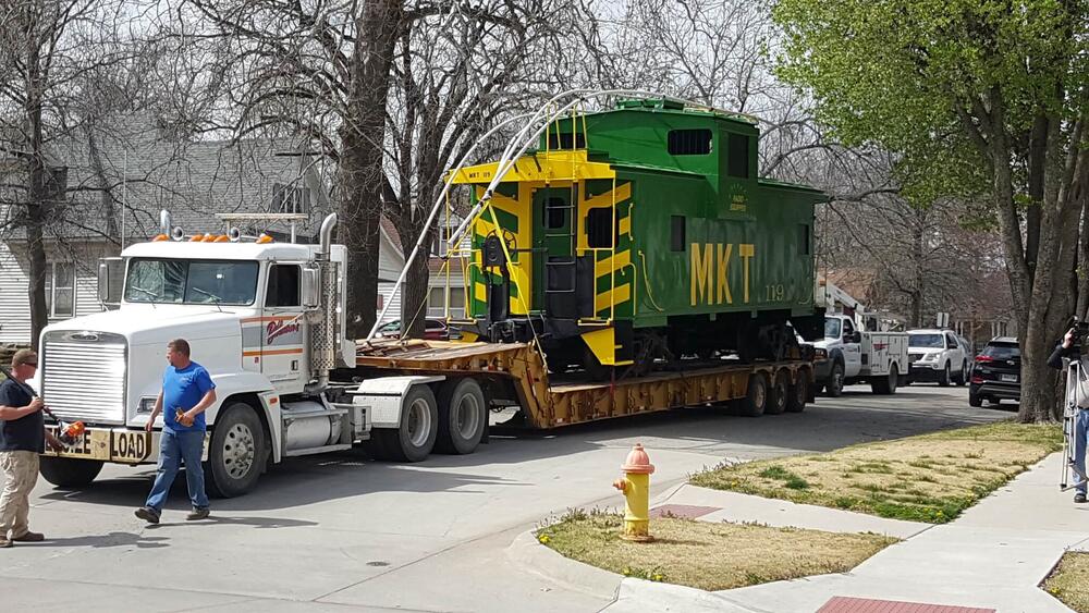 A green caboose being transferred to Parsons